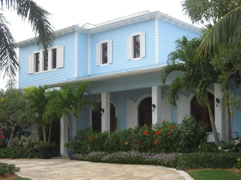 A Key West style two-storey home in light blue with white trim and shutters and an arched loggia
