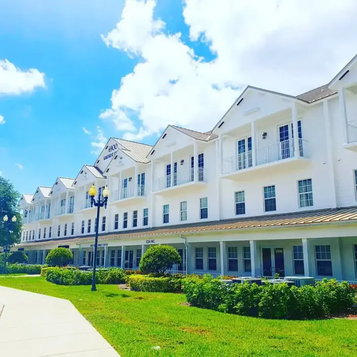A multi-unit white commercial building with standing-seam roofs and landscaped grounds