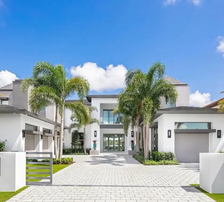 A modern white estate in Boca Raton with a palm-lined paver driveway and gated entry, painted by Creative Images Painting